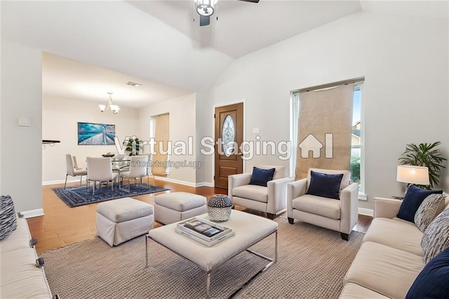 living room with ceiling fan with notable chandelier, lofted ceiling, and hardwood / wood-style flooring