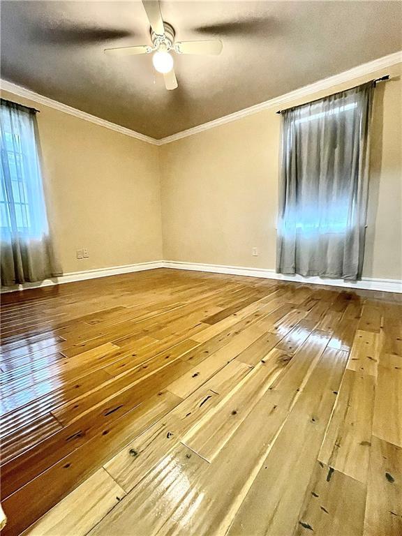 empty room with crown molding, ceiling fan, and wood-type flooring