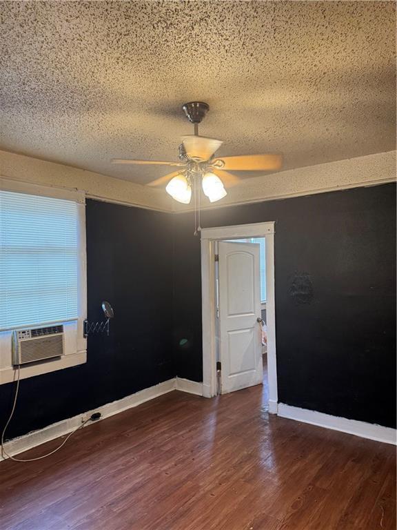 spare room with ceiling fan, dark hardwood / wood-style floors, cooling unit, and a textured ceiling