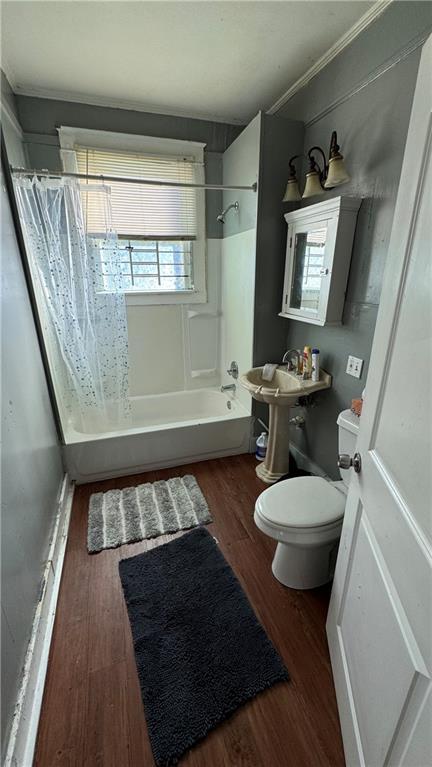 bathroom with wood-type flooring, toilet, and shower / bath combo with shower curtain