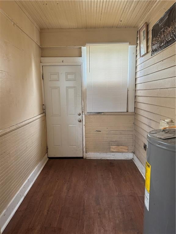 doorway with dark wood-type flooring, wood walls, electric water heater, and wooden ceiling