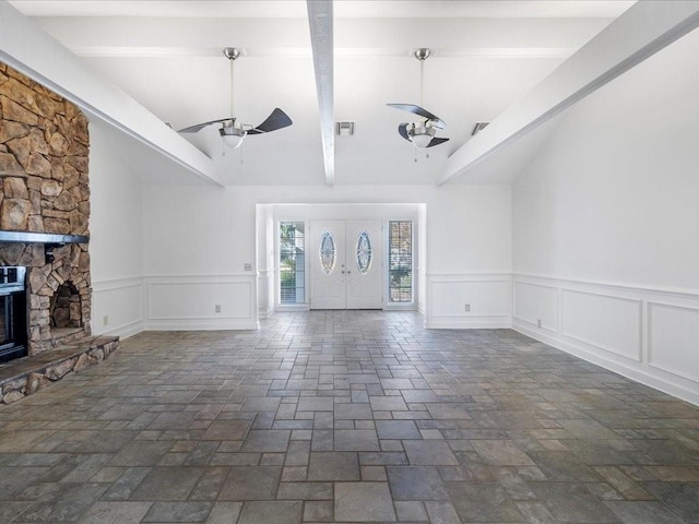 unfurnished living room featuring a fireplace, vaulted ceiling with beams, and ceiling fan