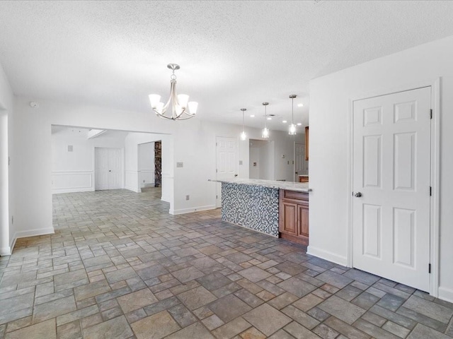 kitchen featuring pendant lighting, a notable chandelier, and a textured ceiling