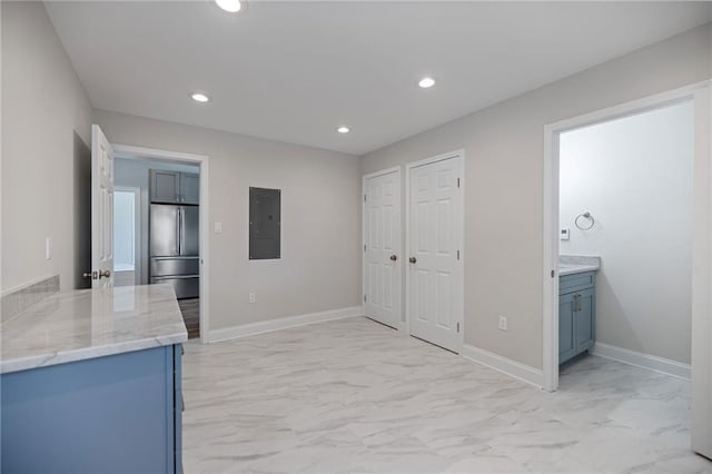 interior space with electric panel, stainless steel fridge, and light stone counters