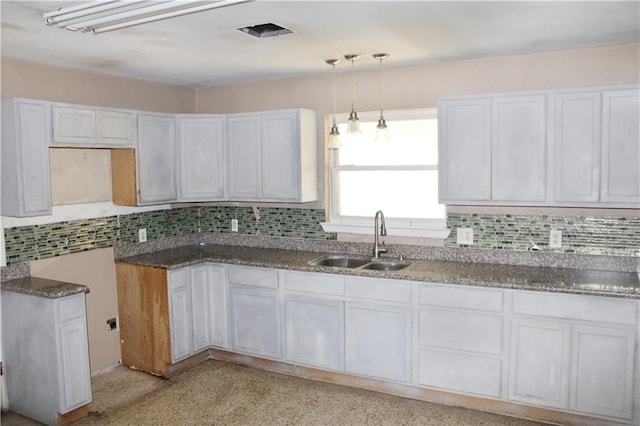 kitchen with white cabinets, decorative light fixtures, backsplash, and sink