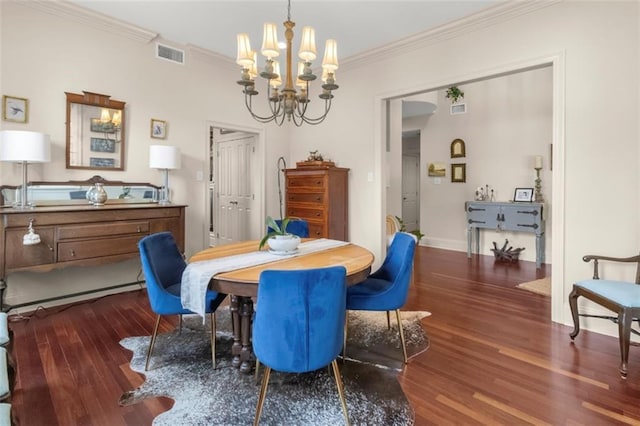 dining room with dark wood-type flooring, ornamental molding, and a chandelier