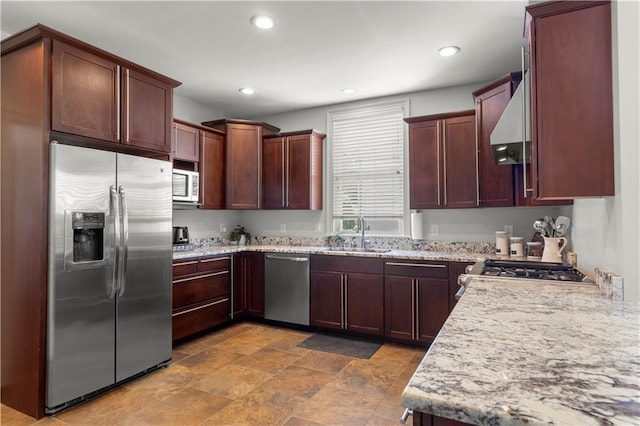 kitchen featuring sink, light stone countertops, wall chimney exhaust hood, and appliances with stainless steel finishes