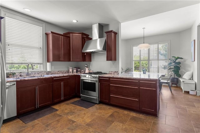 kitchen featuring wall chimney exhaust hood, sink, decorative light fixtures, appliances with stainless steel finishes, and kitchen peninsula