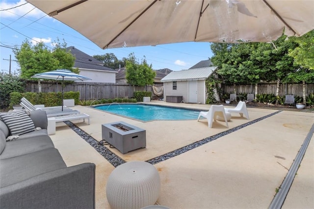 view of pool with a shed, a patio, an outdoor living space with a fire pit, and pool water feature