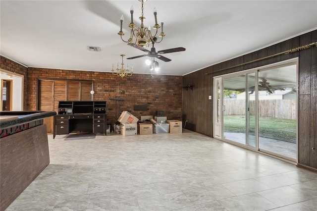 unfurnished living room with an inviting chandelier, wooden walls, and brick wall