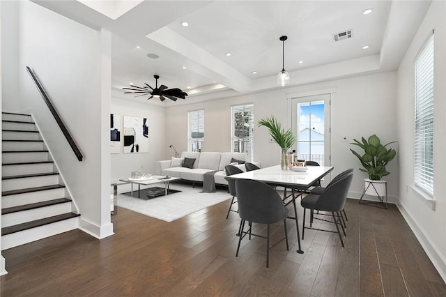 dining space with a tray ceiling, ceiling fan, and dark hardwood / wood-style floors