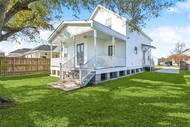 back of property with a yard and covered porch