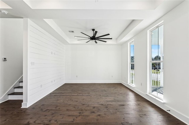 spare room with a tray ceiling, ceiling fan, and dark hardwood / wood-style floors