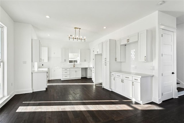 kitchen with a notable chandelier, white cabinetry, hanging light fixtures, and dark wood-type flooring