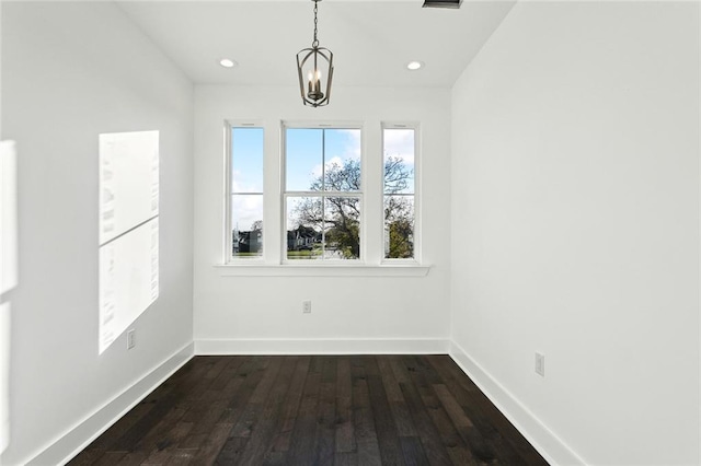 unfurnished dining area featuring a chandelier and dark hardwood / wood-style flooring