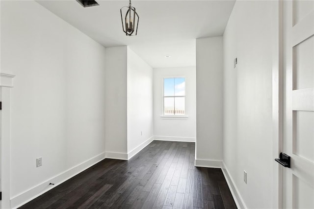 unfurnished room featuring dark hardwood / wood-style floors and an inviting chandelier