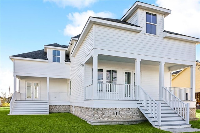 view of front of property with covered porch, french doors, and a front yard