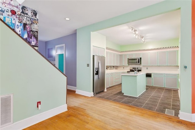 kitchen featuring dark hardwood / wood-style flooring, stainless steel appliances, a kitchen island with sink, sink, and white cabinetry