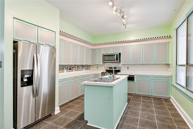 kitchen featuring sink, dark tile patterned floors, a kitchen island with sink, and appliances with stainless steel finishes