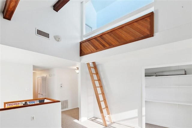 stairway with carpet flooring, beamed ceiling, and high vaulted ceiling