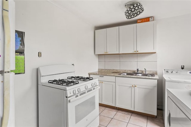 kitchen with decorative backsplash, gas range gas stove, sink, washer / clothes dryer, and white cabinetry