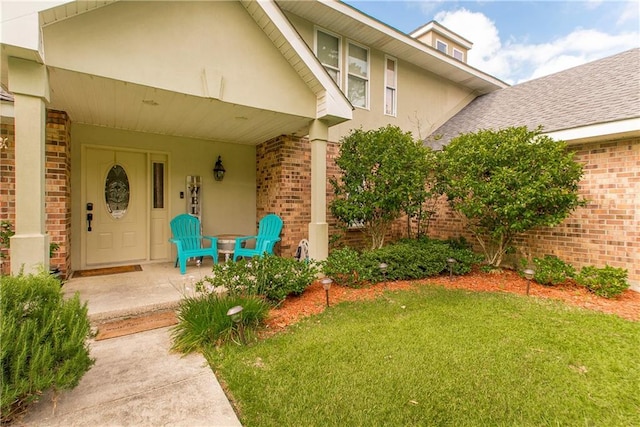 entrance to property with brick siding, stucco siding, and a lawn