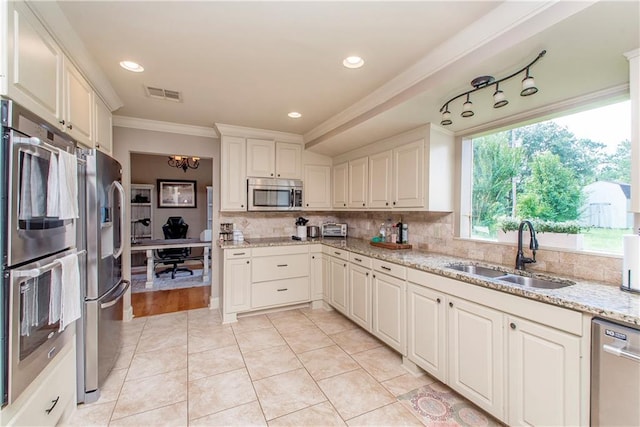 kitchen featuring visible vents, a sink, tasteful backsplash, stainless steel appliances, and crown molding