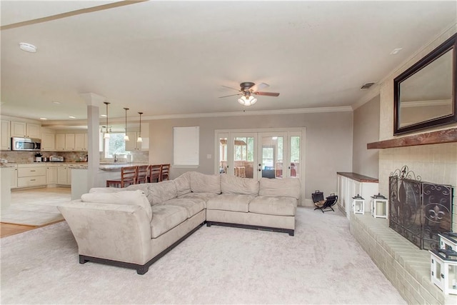 living room with visible vents, ornamental molding, french doors, a brick fireplace, and ceiling fan