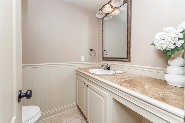 bathroom featuring tile patterned flooring, wainscoting, vanity, and toilet