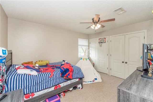 carpeted bedroom featuring a textured ceiling, a ceiling fan, visible vents, and multiple closets