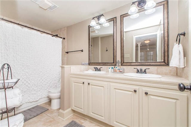 bathroom featuring double vanity, toilet, tile patterned floors, and a sink