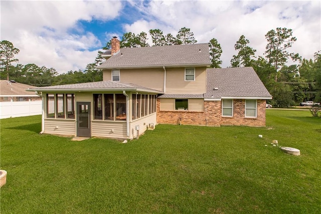 rear view of property featuring a yard, brick siding, a chimney, and a sunroom