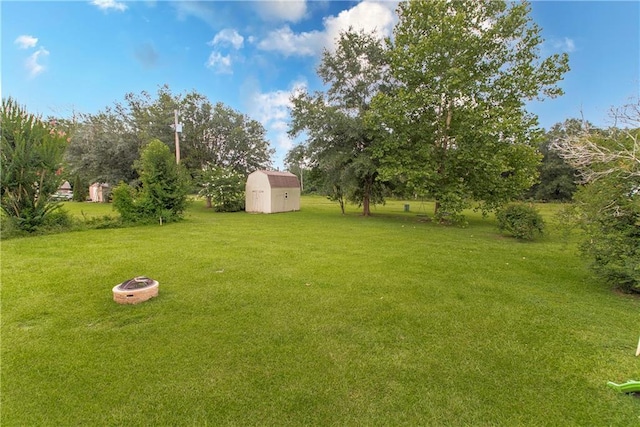 view of yard featuring an outbuilding, a storage unit, and a fire pit