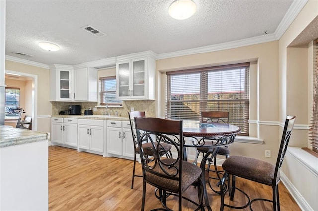 kitchen featuring light wood-type flooring, white cabinetry, and ornamental molding