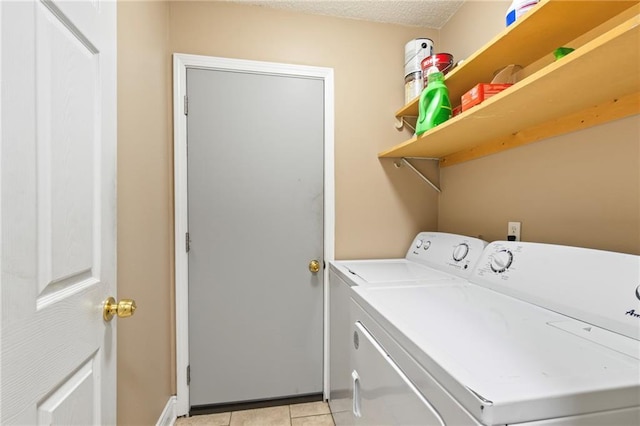 washroom with washer and dryer, light tile patterned flooring, and a textured ceiling