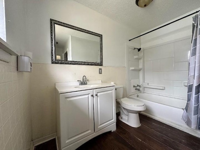 full bathroom with hardwood / wood-style floors, a textured ceiling, shower / bath combo with shower curtain, vanity, and tile walls