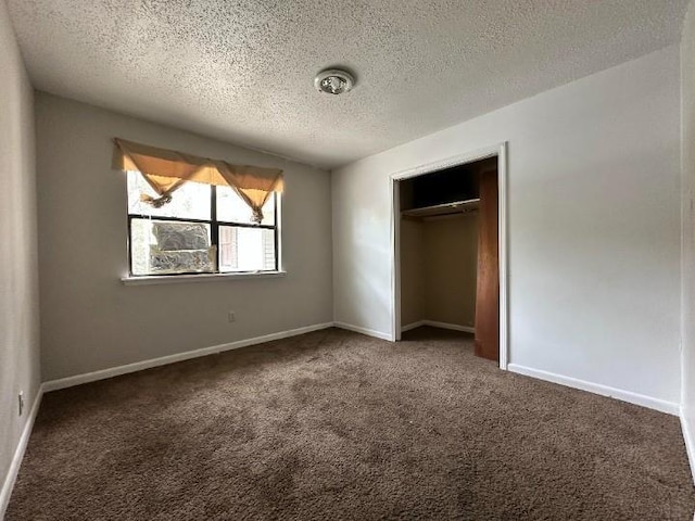 unfurnished bedroom with a closet, dark carpet, and a textured ceiling