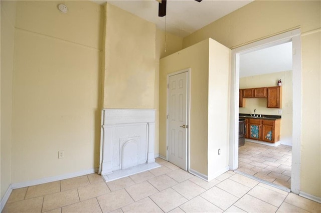 tiled empty room featuring ceiling fan and sink