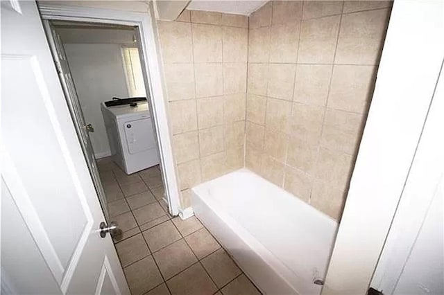 bathroom featuring tile patterned flooring, a bathtub, and washer / dryer