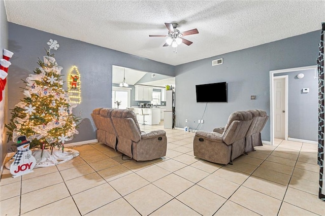 living area with visible vents, baseboards, lofted ceiling, light tile patterned flooring, and a ceiling fan