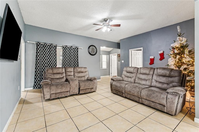 living area with baseboards, a textured ceiling, light tile patterned flooring, and a ceiling fan