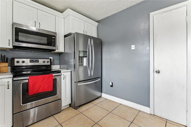 kitchen featuring stainless steel appliances, light tile patterned flooring, light countertops, and white cabinetry