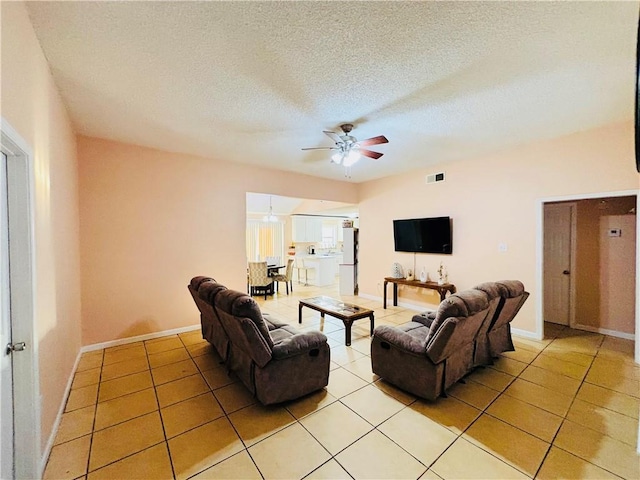 living area with light tile patterned floors, baseboards, a textured ceiling, and ceiling fan