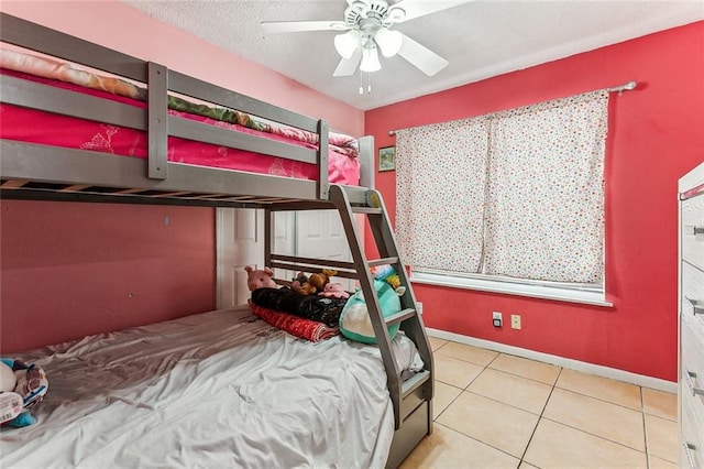 bedroom with tile patterned floors, a textured ceiling, baseboards, and a ceiling fan