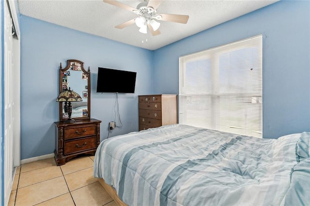 bedroom featuring a textured ceiling, light tile patterned flooring, baseboards, and ceiling fan