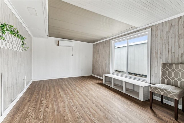 interior space featuring a wall mounted air conditioner, crown molding, baseboards, and wood finished floors