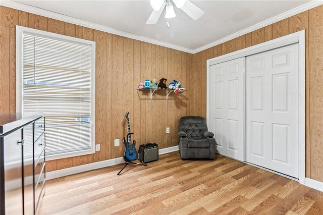 living area featuring ceiling fan, ornamental molding, and light wood finished floors