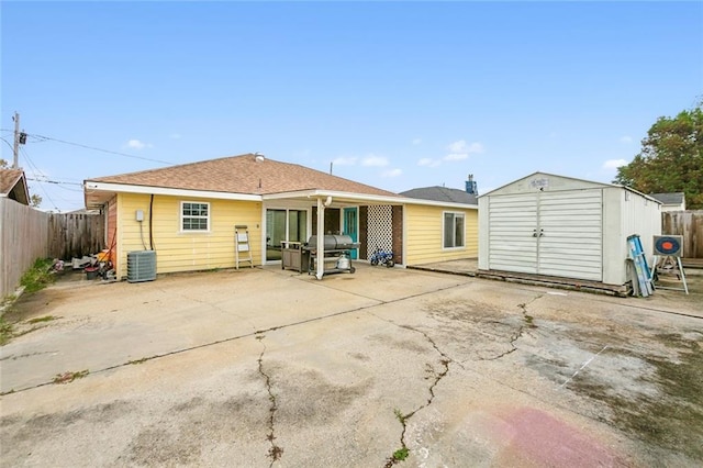 back of house featuring a storage unit, an outbuilding, central AC, a fenced backyard, and a patio area