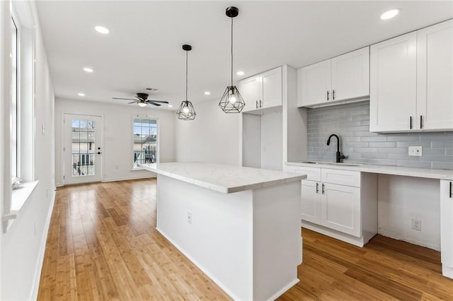 kitchen featuring backsplash, white cabinets, sink, ceiling fan, and decorative light fixtures