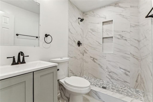 bathroom with toilet, vanity, and tiled shower